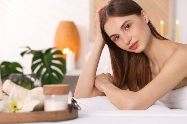 Güzel bir kadın masaj salonundaki masaj koltuğunda dinleniyor, seçici bir odak noktası.