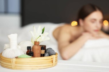 Kadın kuaförde dinleniyor, spa ürünlerine ve çiçeklere odaklanıyor