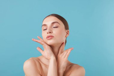 Açık mavi arka planda büyüleyici genç bir kadının portresi.