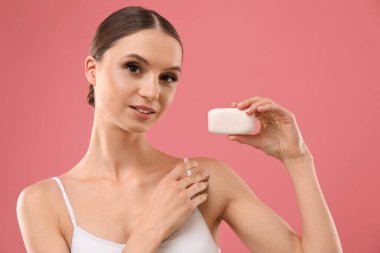 Pembe arka planda sabun çubuğu olan güzel bir kadın.