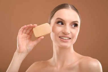 Kahverengi arka planda sabun çubuğu olan gülümseyen kadın, yakın plan.