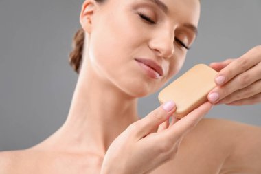 Gri arka planda sabun çubuğu olan güzel kadın, yakın plan.