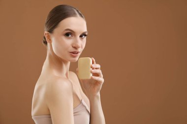 Kahverengi arka planda sabun çubuğu olan güzel bir kadın. Metin için boşluk