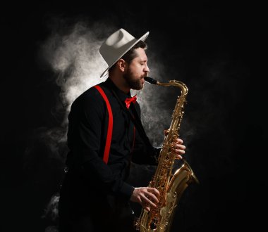 Profesyonel müzisyen siyah arka planda dumanla saksafon çalıyor. Metin için boşluk