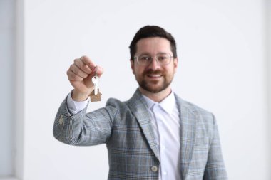 Emlakçının elinde ev şeklindeki anahtarlık var.