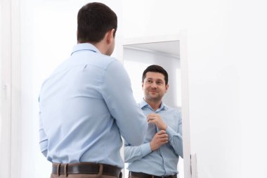 Yakışıklı adam aynada kendine bakıyor.