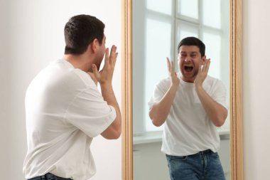 Yakışıklı adam aynada kendine bakıyor.