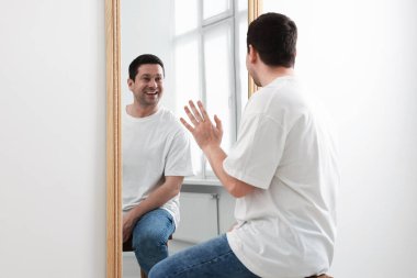 Yakışıklı adam aynada kendine bakıyor.