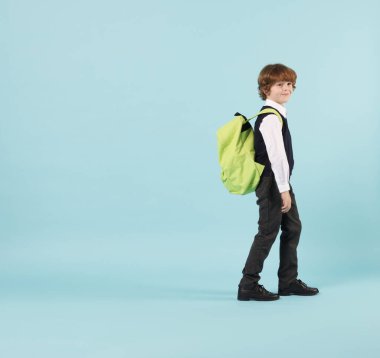 Açık mavi arka planda sırt çantası olan sevimli okul çocuğu, mesaj için yer var.