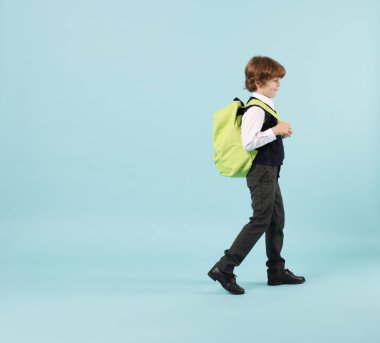 Açık mavi arka planda sırt çantası olan sevimli okul çocuğu, mesaj için yer var.