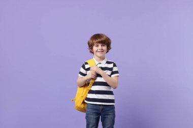 Menekşe arka planda sırt çantası olan tatlı bir okul çocuğu.