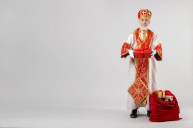 Açık gri arka planda hediyelerle dolu bir çuval dolusu Aziz Nicholas. Metin için boşluk