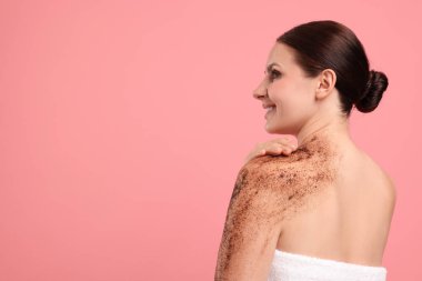 Gülümseyen kadın omzunu pembe arka plana sürterek ovalıyor. Metin için boşluk