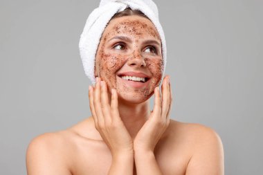 Yüzü gri arka planda, gülümseyen bir kadın.