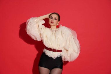 Kırmızı arka planda şık giyinmiş genç bir kadın.