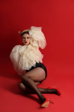 Kırmızı arka planda şık giyinmiş genç bir kadın.