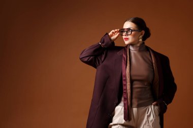 Kahverengi arka planda şık giyinmiş genç kadın, mesaj için yer var.