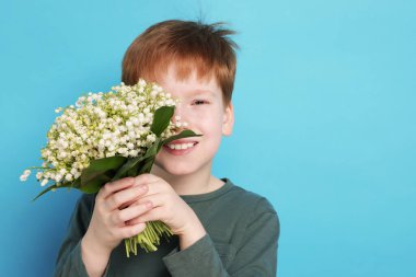 Açık mavi arka planda, vadideki güzel çiçekleri olan çocuk.