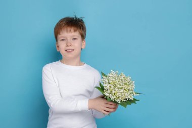 Açık mavi arka planda, vadideki güzel çiçekleri olan çocuk.