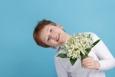 Açık mavi arka planda, vadideki güzel çiçekleri olan çocuk.