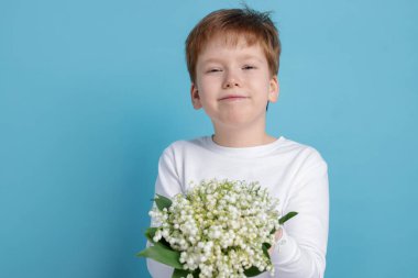 Açık mavi arka planda, vadideki güzel çiçekleri olan çocuk.