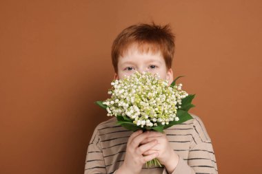 Kahverengi arka planda vadideki güzel çiçekleri olan bir çocuk.