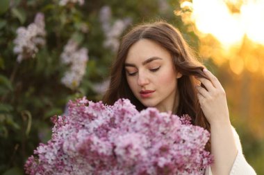 Güzel bir kadın portresi ve açık havada leylak çiçekleri.