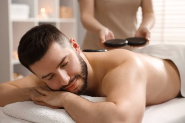 Adam spa salonunda taşlarla masaj yaptırıyor.
