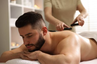 Adam spa salonunda taşlarla masaj yaptırıyor.
