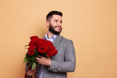 Bej arka planda kırmızı gül buketi olan mutlu adam, metin için boşluk.