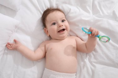 Evde yatağında çıngıraklı oyuncağı olan sevimli bir bebek.