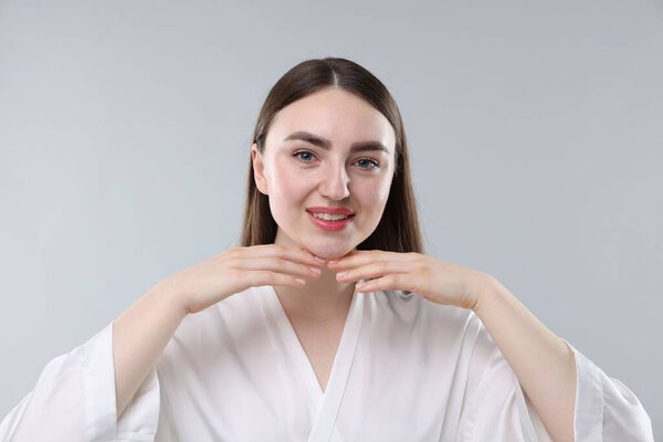 Улыбающаяся женщина со здоровой кожей на сером фоне