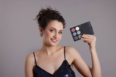 Gri arka planda göz falı olan gülümseyen kadın.