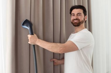 Evde buharlı perdeleri olan bir adam.