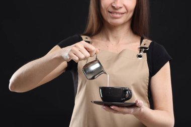 Gülümseyen barista siyah arka planda kahve yapıyor, yakın plan.