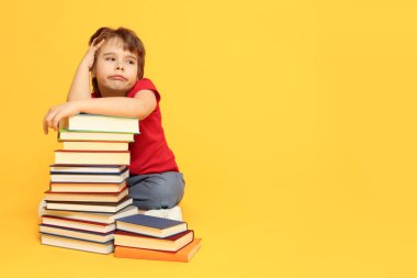 Turuncu arka plan kitapları olan üzgün bir çocuk. Metin için boşluk