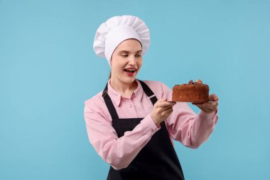 Açık mavi arka planda lezzetli çikolatalı pasta yapan bir pastacı.