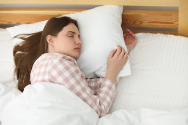 Genç bir kadın yatağında uyuyor.