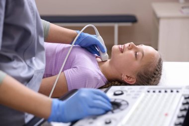 Sonograf, klinikte kızın tiroid bezi ultrason muayenesini yönetiyor.
