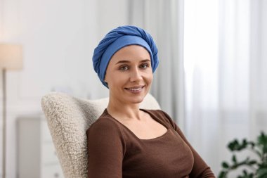 İçerideki koltukta türbanlı kanserli gülümseyen kadının portresi.
