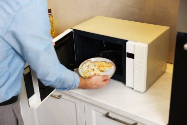 Yemek tabağını mikrodalgaya koyan adam, yakın plan.