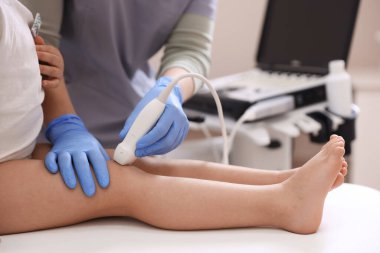 Sonograf, klinikte küçük kızın dizinin ultrason muayenesini yapıyor.