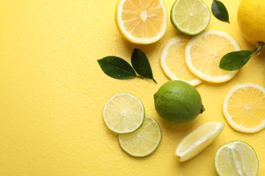 Taze limon, limon ve yeşil yapraklar sarı arka planda, düz yerde. Metin için boşluk