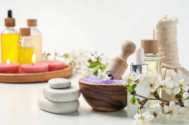Kozmetik ürünleriyle spa kompozisyonu, güzel çiçekler ve beyaz arka planda yanan mumlar, seçici odak