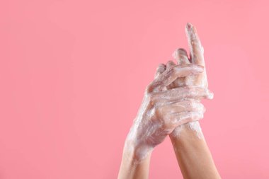 Açık pembe arka planda ellerini sabunla yıkayan kadın, yakın plan. Metin için boşluk