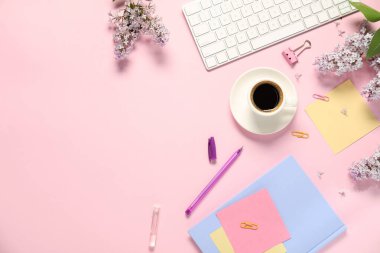 Pembe zemin üzerinde kırtasiye ve çiçeklerle düz kompozisyon, metin için boşluk