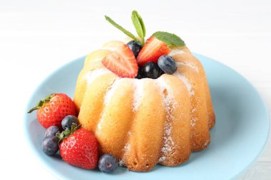 Beyaz masada pudra şekeri ve böğürtlenli leziz kek, yakın plan.