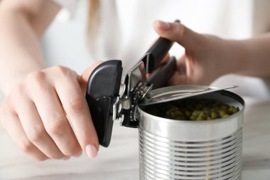 Beyaz masada konserve açacağıyla konserve açan kadın, yakın çekim