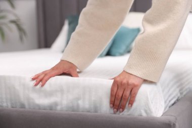 Yatağa yeni yumuşak bir yatak koyan kadın, yakın plan.