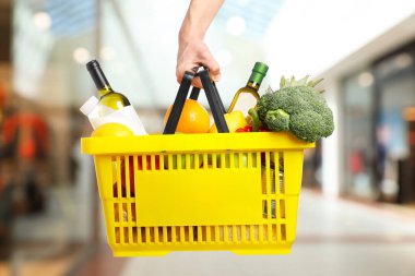 Süpermarkette elinde farklı gıda ürünleri olan bir adam var.